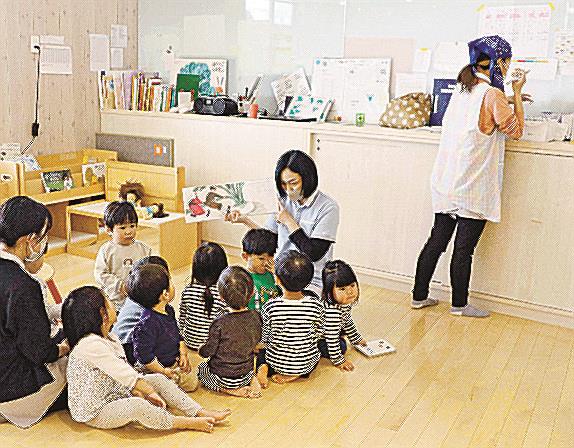 国の基準よりも多く保育士を配置している東京都内の保育園。他の保育士が子どもの面倒を見る傍ら、１人（右端）は連絡帳の記入に専念していた＝３月
