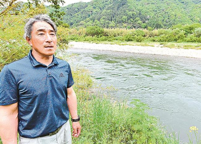 自宅近くを流れる江の川のほとりに立ち、「住民それぞれの思いを聞き、プランをつくってほしい」と語る渡崇さん＝江津市桜江町大貫