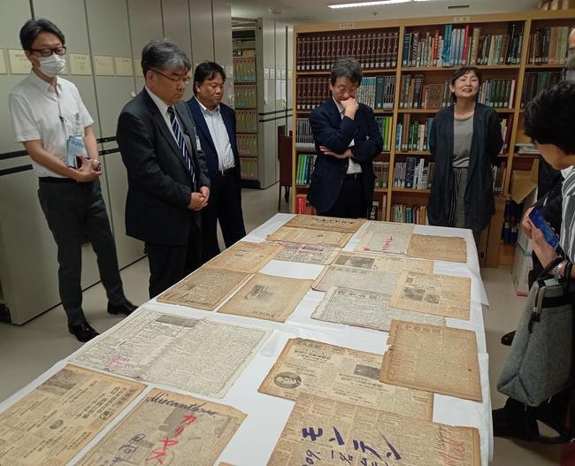 牧野富太郎が植物標本の収集で使った全国の新聞紙を紹介する学芸員（右奥）＝７日、高知市の牧野植物園