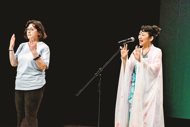 手話をしながら歌うＲｉｔｓｕｋｏさん（右）と松江南高の卒業生＝松江市殿町、県民会館