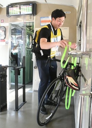 ２０２４年７月にＪＲ米子駅で行われた実証実験で、列車内に自転車を持ち込む参加者（資料）