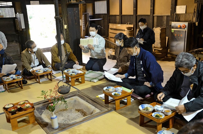 並ぶ料理とともに文書にある献立の解説を聴く参加者＝島根県隠岐の島町釜、佐々木家住宅