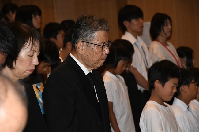 慰霊祭に参列した子どもたちとともに黙とうする、大山口列車空襲被災者の会の金田吉人会長（中央）＝鳥取県大山町赤坂