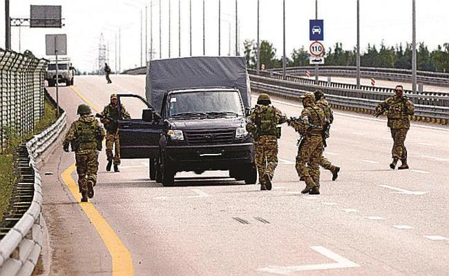 ロシア南部とモスクワをつなぐ道路で車両の近くを歩くワグネルの戦闘員＝２４日、ロシア・ボロネジ近郊（ロイター＝共同）