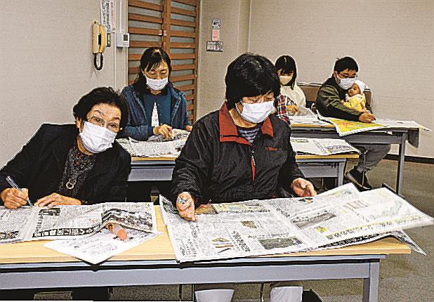 山陰中央新報の紙面に目を通す参加者＝島根県邑南町山田、出羽公民館