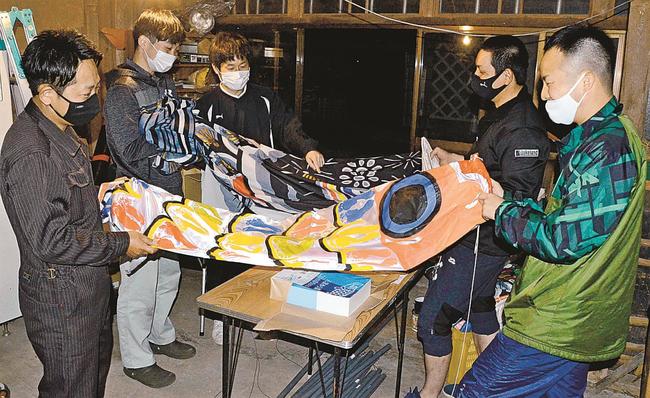 掲揚当日に向け、こいのぼりにひもを通すメンバーたち＝松江市八雲町東岩坂