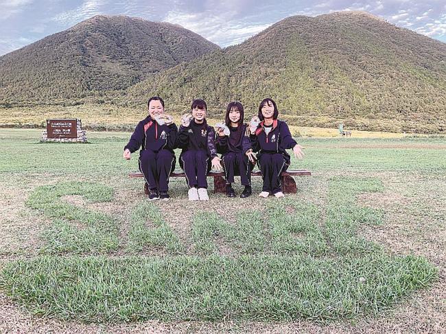 芝生をＳＡＮＢＥの文字に刈り込み、記念写真を撮る大田高校の生徒たち＝大田市三瓶町