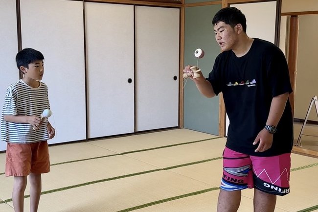 手本を見せる森欣空さん（右）。隠岐の島町内の子どもたちに指導する日々だ＝6月、島根県隠岐の島町西町・隠岐島文化会館