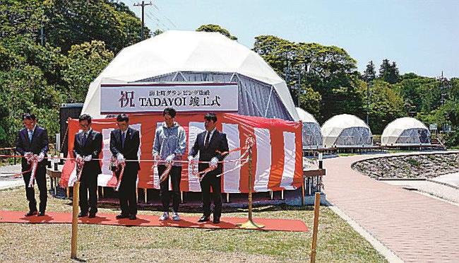 グランピング施設のドーム形テントをバックにテープカットする関係者＝島根県海士町福井