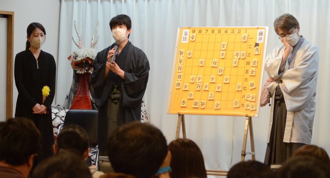 将棋の第７２期王将戦７番勝負第５局の終了後、大盤解説会の会場で激闘を振り返る勝者の藤井聡太王将（中央）と敗れた羽生善治九段（右）。左は解説した里見香奈女流五冠＝大田市三瓶町、国民宿舎さんべ荘