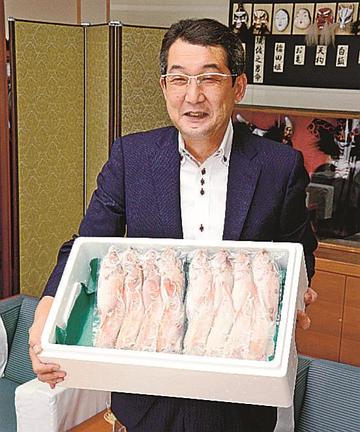 浜田市内の学校給食で提供する「どんちっちノドグロ」を手にする金坂敏弘会長＝浜田市殿町、市役所