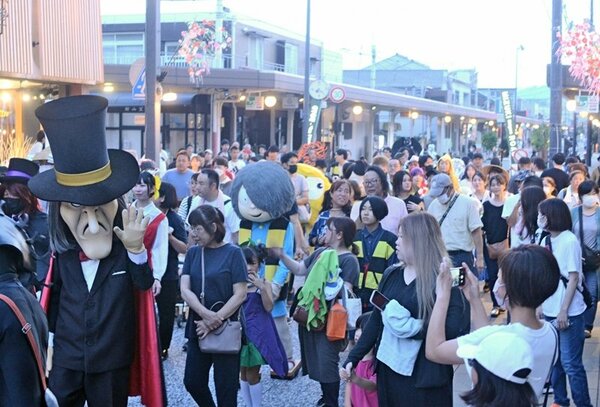 土曜夜市のにぎわいの中、妖怪仮装パレードで水木しげるロードを練り歩く参加者＝境港市本町