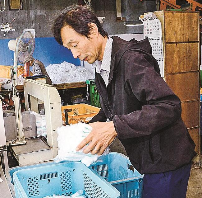 取引先へ配達するおしぼりを準備する野津照己社長＝松江市西川津町、城北ドライ