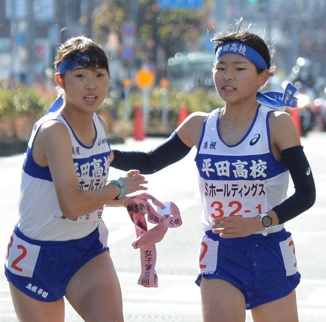 １区森山紗仁美（右）からたすきを受け、走り出す２区来間美月（左）＝平野神社前、第１中継所