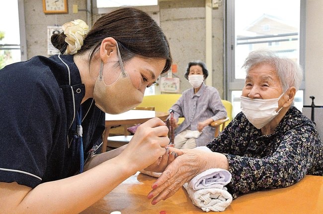 手の爪にネイルをしてもらって笑顔を見せる入居者（右）＝江津市和木町、よろこぼう屋