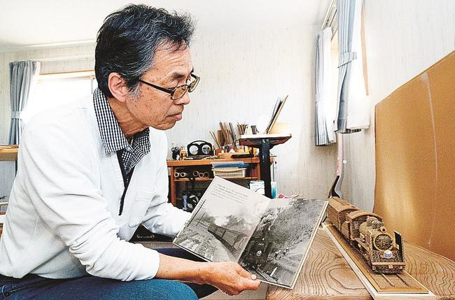 自宅アトリエで写真集と段ボールクラフトのＳＬを鑑賞する原禎幸さん＝出雲市湖陵町三部