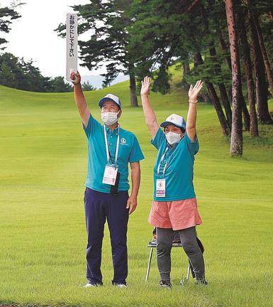 観客に制止を促すボランティア業務に従事する垣内徹司さん、功子さん夫婦＝鳥取県伯耆町丸山、大山平原ゴルフクラブ