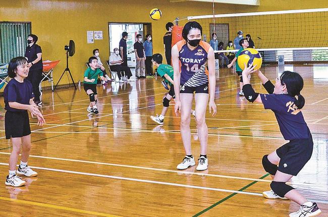 大崎琴未選手（中央）からオーバートスの指導を受ける児童＝松江市矢田町、矢田体育館