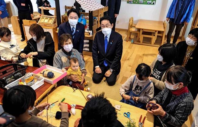 「異次元の少子化対策実施」に向け、子育て支援施設を視察する岸田首相（画面中央）。政府は公表した試案を国民的議論のたたき台とする＝２月、岡山県奈義町（代表撮影）