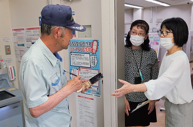 電話で話しながらＡＴＭを操作していた客（左）に声をかける行員＝島根県川本町川本、山陰合同銀行川本支店