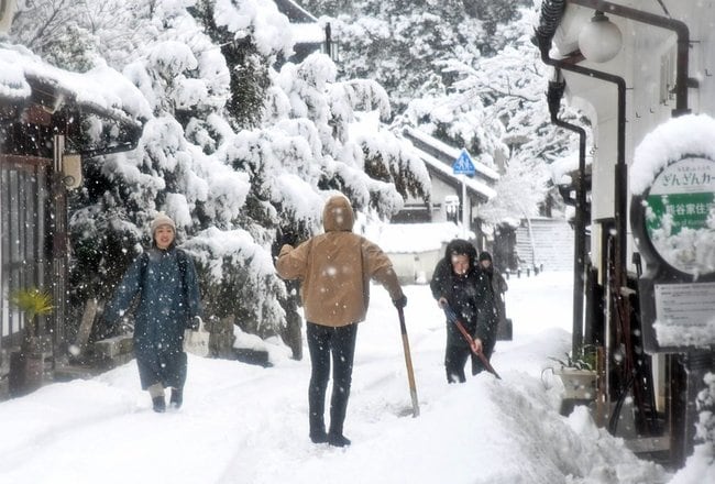 世界遺産・石見銀山遺跡の町並みで雪かきをする住民ら＝２３日午前８時４９分、大田市大森町