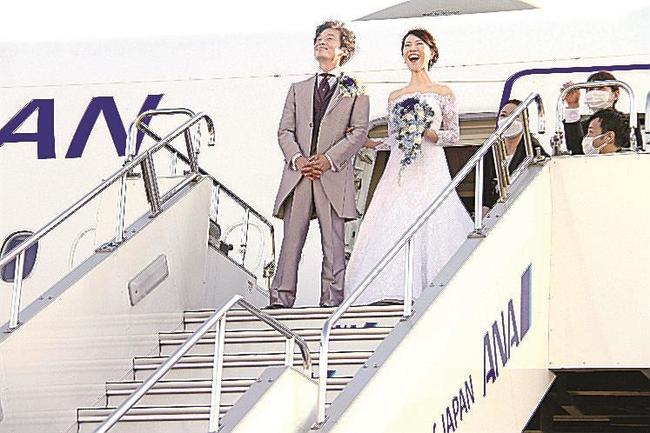 「機内ウエディング」を終え、タラップで笑顔を見せる新郎の村上徹さんと新婦の麻美さん＝２３日午後、羽田空港