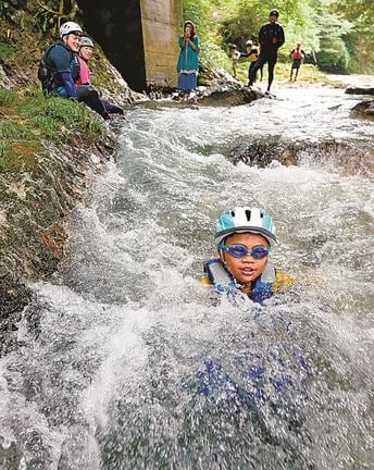 流れに乗って沢谷川を滑り降りる参加者＝島根県美郷町九日市