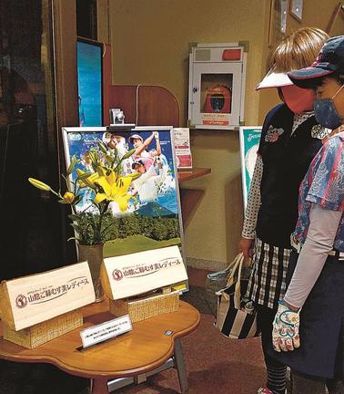 「山陰ご縁むす美レディース」の特製ティーマークに見入る女性ゴルファー＝鳥取県伯耆町丸山、大山平原ゴルフクラブ