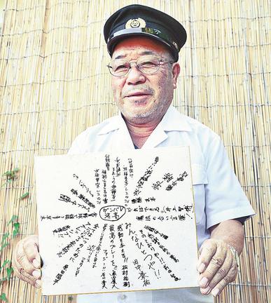 ２００４年の夏の甲子園に出場した浜田高ナインの寄せ書きを手にする岡田智さん＝浜田市三隅町井野