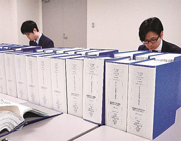 ２０２２年分の政治資金収支報告書（総務相所管の中央分）。奥はチェックする職員＝２１日、総務省