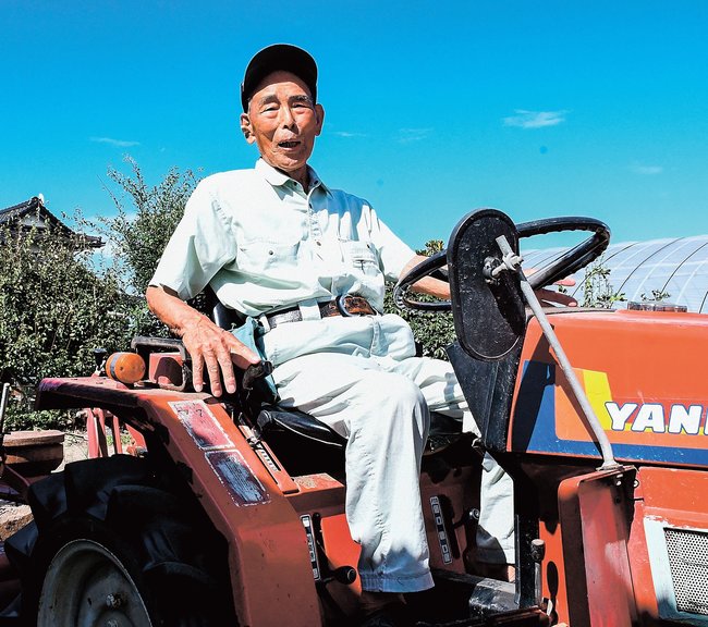 耕運機に乗って畑を耕す福田幸市さん＝出雲市斐川町沖洲