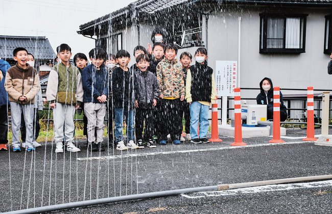 災害時協力井戸（右奥）から引き、噴き出す水に歓声を上げる児童＝鳥取県岩美町大谷、岩美西小学校