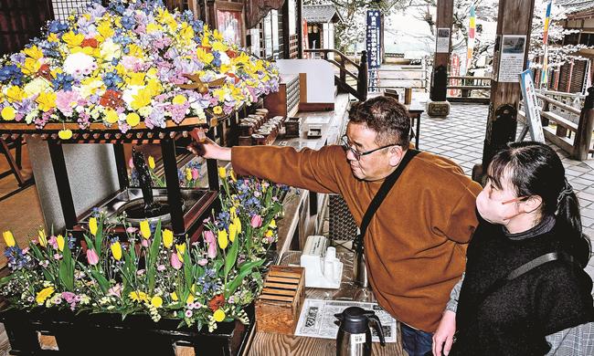 花御堂の釈迦像に甘茶をかける参拝者＝出雲市小境町、一畑薬師