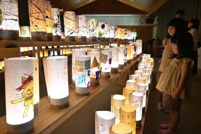 点灯された灯ろうを眺める子どもたち＝浜田市三隅町湊浦、三保まちづくりセンター