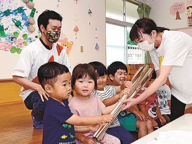 トーチを手に取る園児たちと加藤郁海さん（左）＝島根県飯南町上赤名、町立赤名保育所