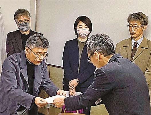 松江市建築審査課の職員（手前右）に要望書を手渡す景観審議委員の金坂浩史委員＝同市末次町、市役所