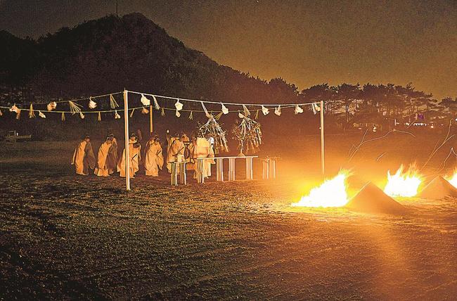 かがり火がたかれる中、神迎神事を行う神職たち＝出雲市大社町杵築北