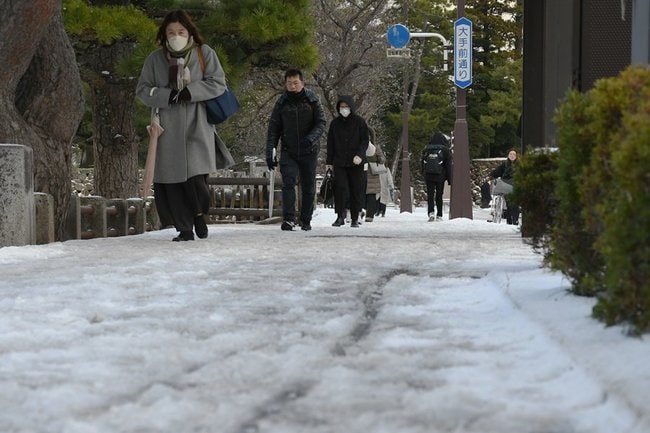 雪が積もった歩道を慎重に歩く市民＝２２日午前８時１０分、松江市殿町