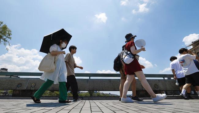 厳しい暑さの中、日傘やうちわで暑さをしのぐ人たち＝２８日午前、京都市