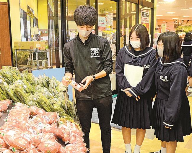 店頭に並ぶ「とまとまるドレッシング」を確認する板本大輝さん（左）ら浜田商業高校の生徒＝浜田市黒川町、キヌヤプリル店
