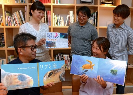 絵本の完成を喜ぶ製作実行委員会のメンバー＝島根県隠岐の島町中町、隠岐ジオゲートウェイ