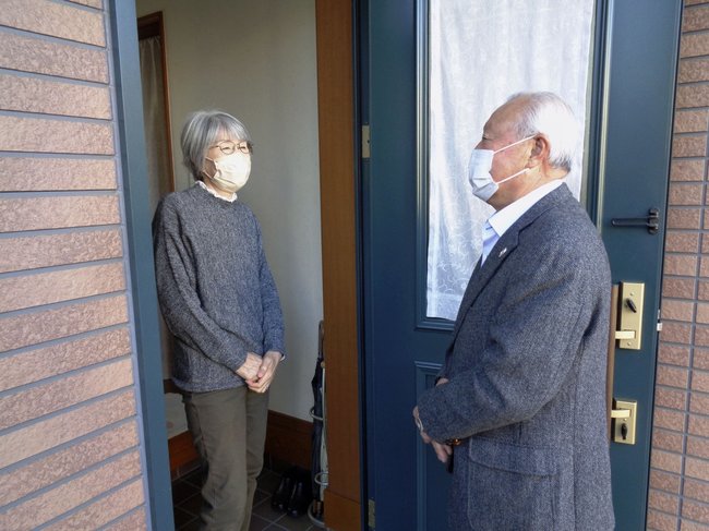 夫を自宅で介護する女性（左）を訪問する民生委員の男性＝２０２２年、川崎市