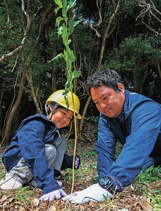 ヤマザクラの苗木を植える親子＝松江市西川津町、楽山公園