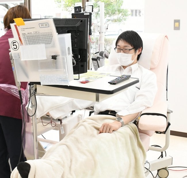 献血しながらテレビを観賞する記者＝松江市大輪町、島根県赤十字血液センター