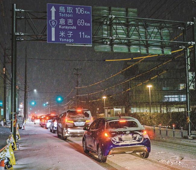 雪で渋滞し車列が続く安来市街の国道９号。右奥が市役所＝２４日午後６時１５分ごろ、安来市安来町（画像を一部加工しています）