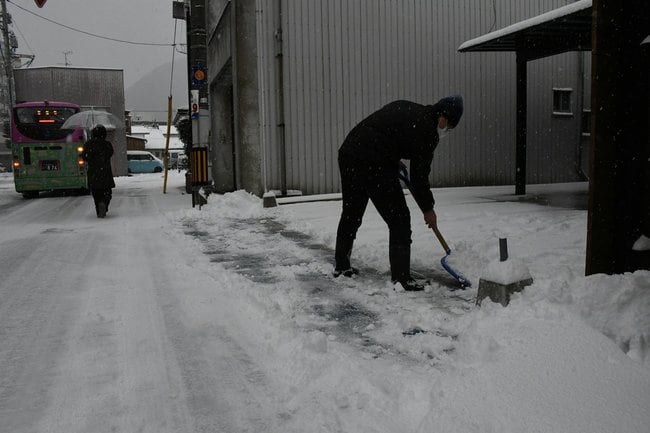 店先の雪かきをする男性=22日午前10時、島根県隠岐の島町中町