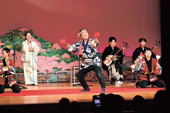 銭太鼓を披露する岩佐菊正さん(中央)=安来市古川町、安来節演芸館