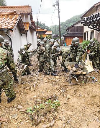 道路上に流れ出た土砂を撤去する自衛隊員=8日午前9時、出雲市猪目町(陸上自衛隊出雲駐屯地提供)
