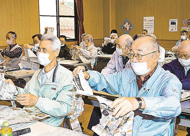 笑顔で新聞を破る参加者＝雲南市木次町木次、三新塔交流センター