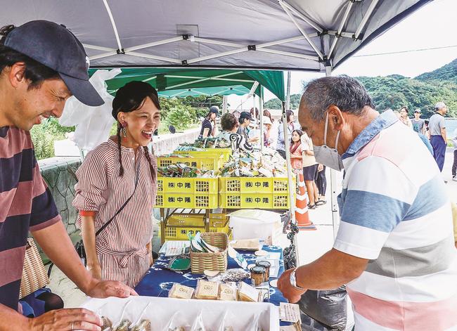 来場客と笑顔で会話する出店者（左）＝松江市美保関町北浦、北浦海水浴場